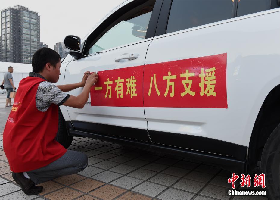 出发前往九寨沟地震灾区运送物资的车辆贴"一方有难 八方支援"标语