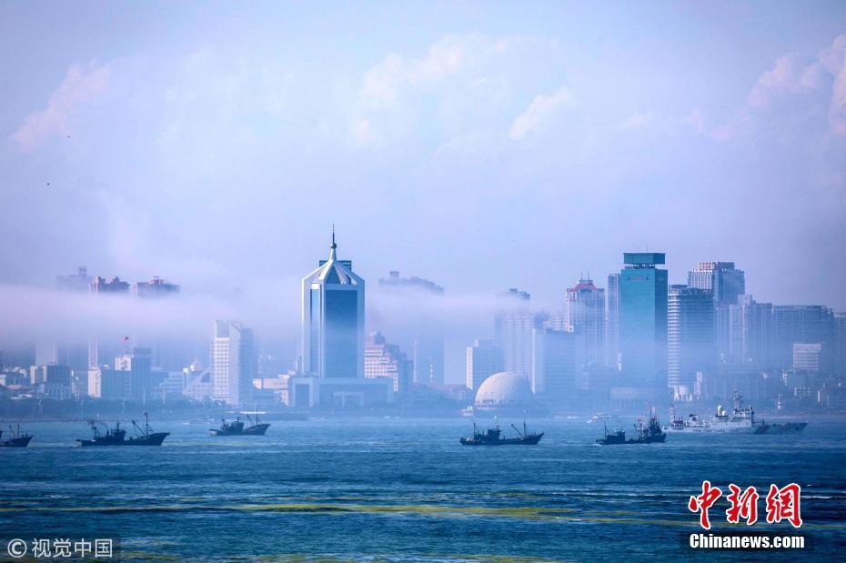 在平流雾的笼罩下,远处的城市高楼如梦似幻,一幅缥缈如幻境的美景