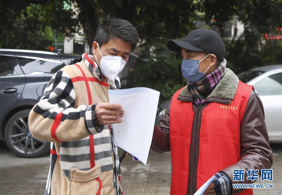 2月3日,重庆市万州区牌楼街道石峰社区志愿者(右)向居民发放疫情