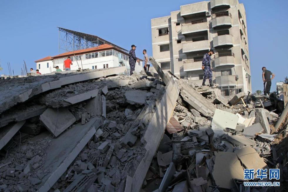 5月14日,巴勒斯坦警察和民众在加沙城查看被以军空袭摧毁的哈马斯银行