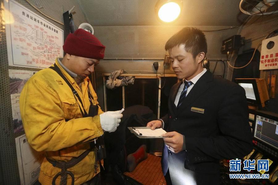 12月31日凌晨,玉林車務段貴港站的調車長甘少寧(左)向火車司機安排