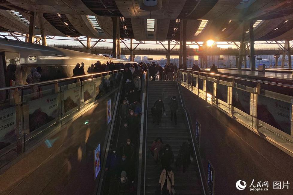 夕阳下,g12抵达北京南站,旅客纷纷下车出站.(人民网记者 翁奇羽 摄)