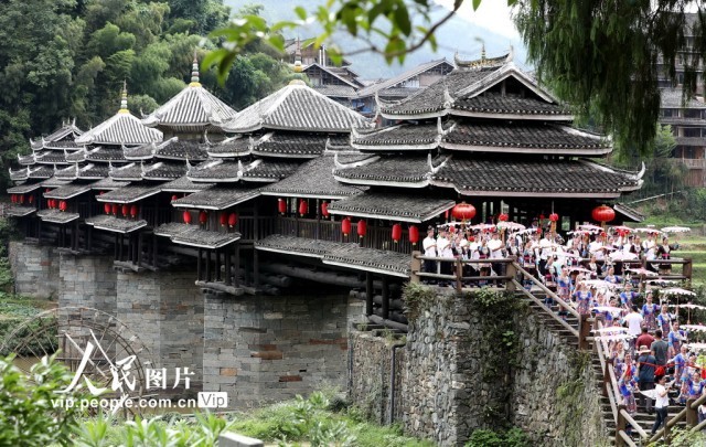 2024年6月8日，在广西三江侗族自治县林溪镇的程阳八寨，村民在风雨桥头迎接游客。